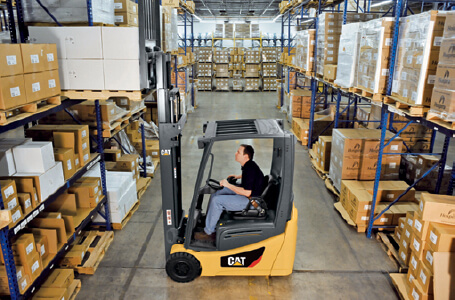 Worker lifting boxes off shelf with Cat forklift