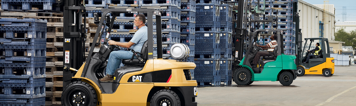Cat, Mitsubishi and Jungheinrich forklifts lined up lifting crates